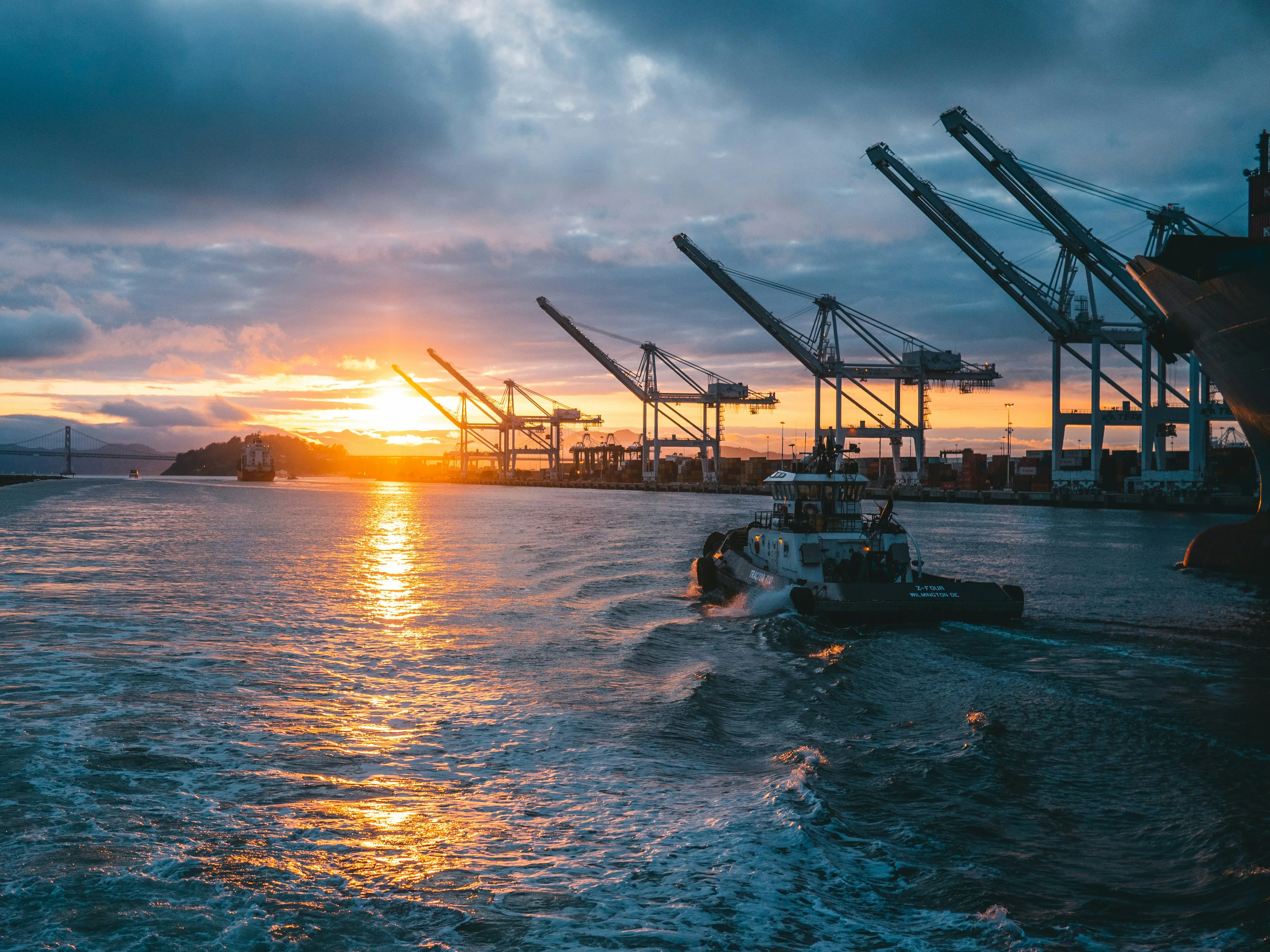 Industrial port with cranes and ships at sunset